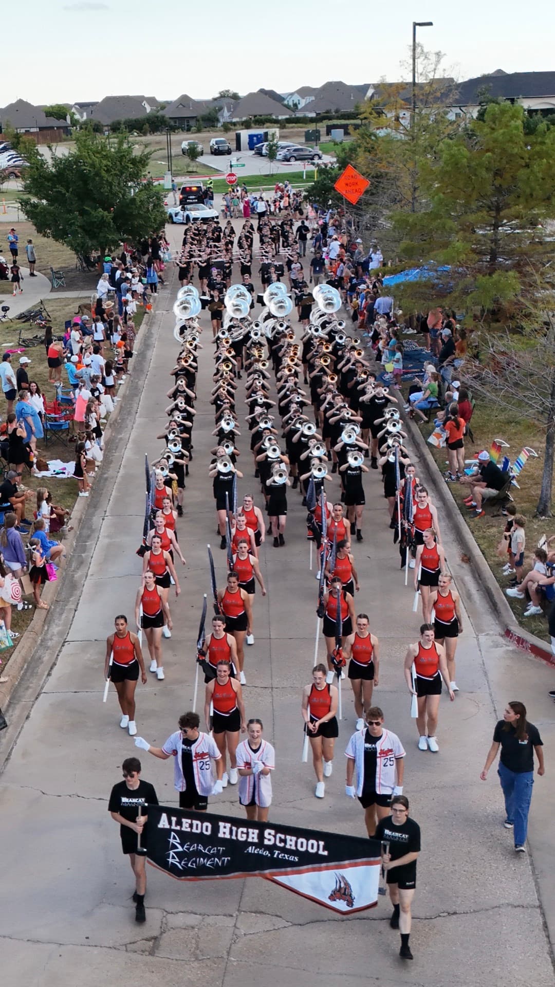 Aerial drone photo of Aledo High School Bearcat Regiment marching band leading homecoming parade through neighborhood streets