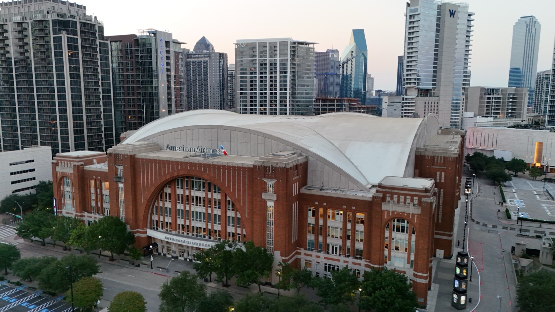 Aerial drone photo of American Airlines Center arena in downtown Dallas at blue hour with city skyline and surrounding buildings