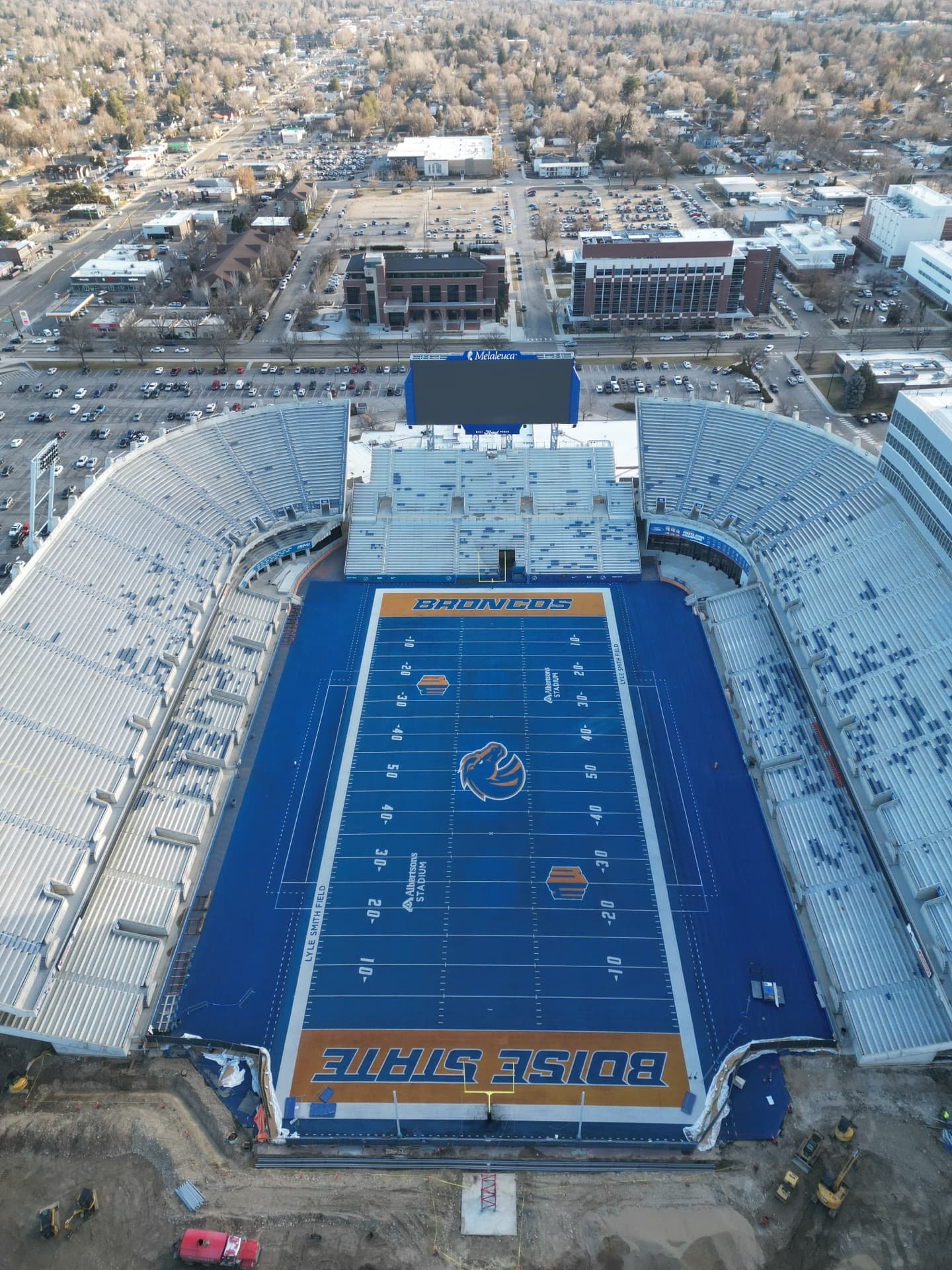 Overhead aerial of Boise State Albertsons Stadium showing blue turf field with "BOISE STATE" end zone and surrounding campus