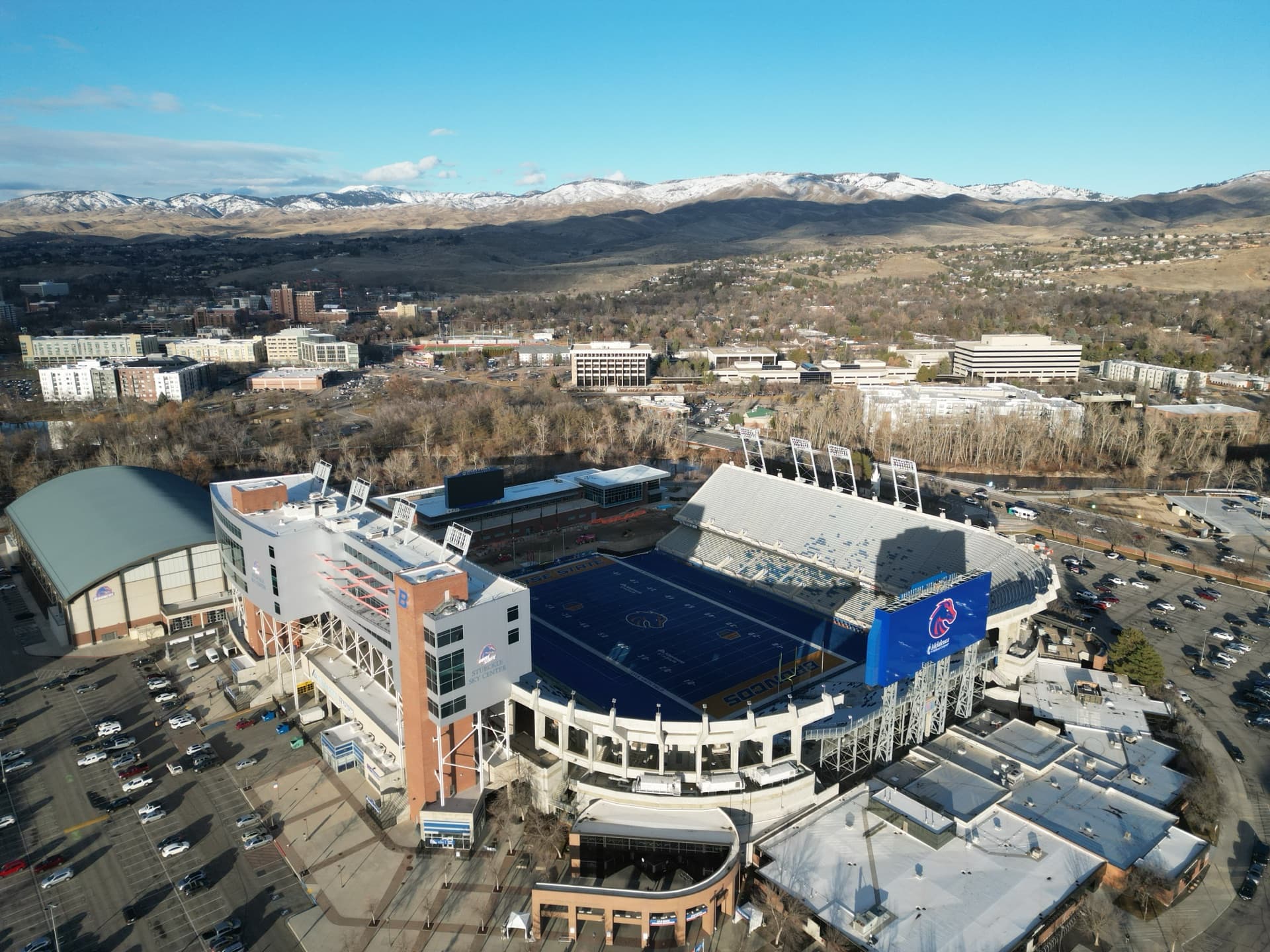 Aerial drone photo of Boise State Broncos Albertsons Stadium with famous blue turf field, campus, and snow-capped mountains