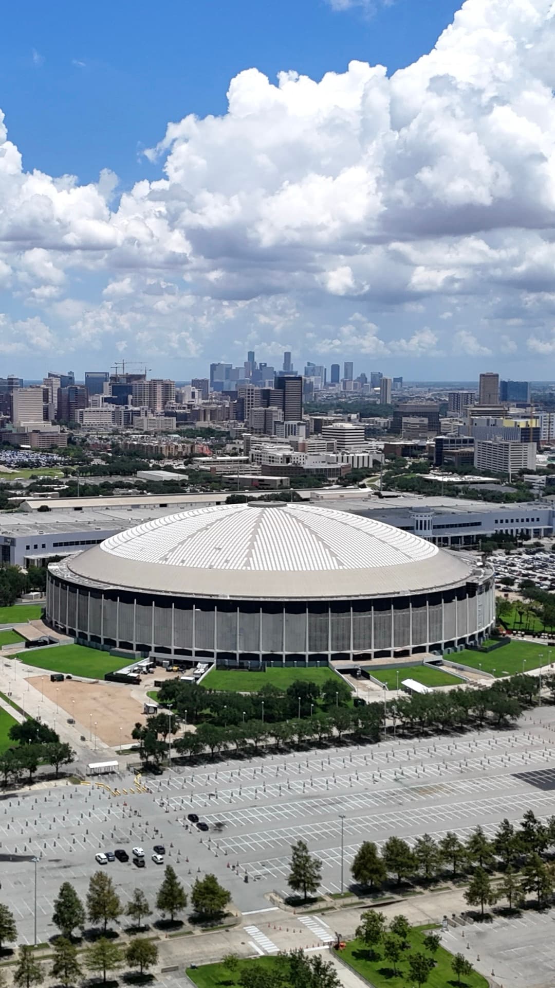 Vertical aerial of historic Houston Astrodome dome with downtown Houston skyline and city landscape stretching to the horizon