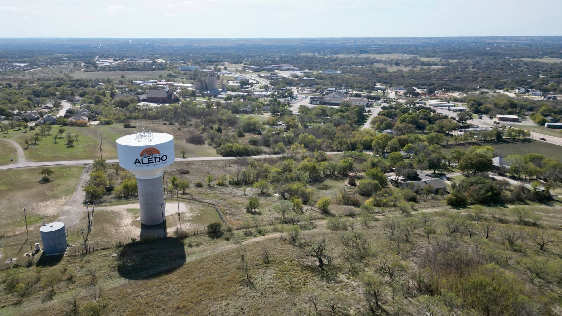 Aerial drone photo of the Aledo Texas water tower with the small town and surrounding countryside visible in the background