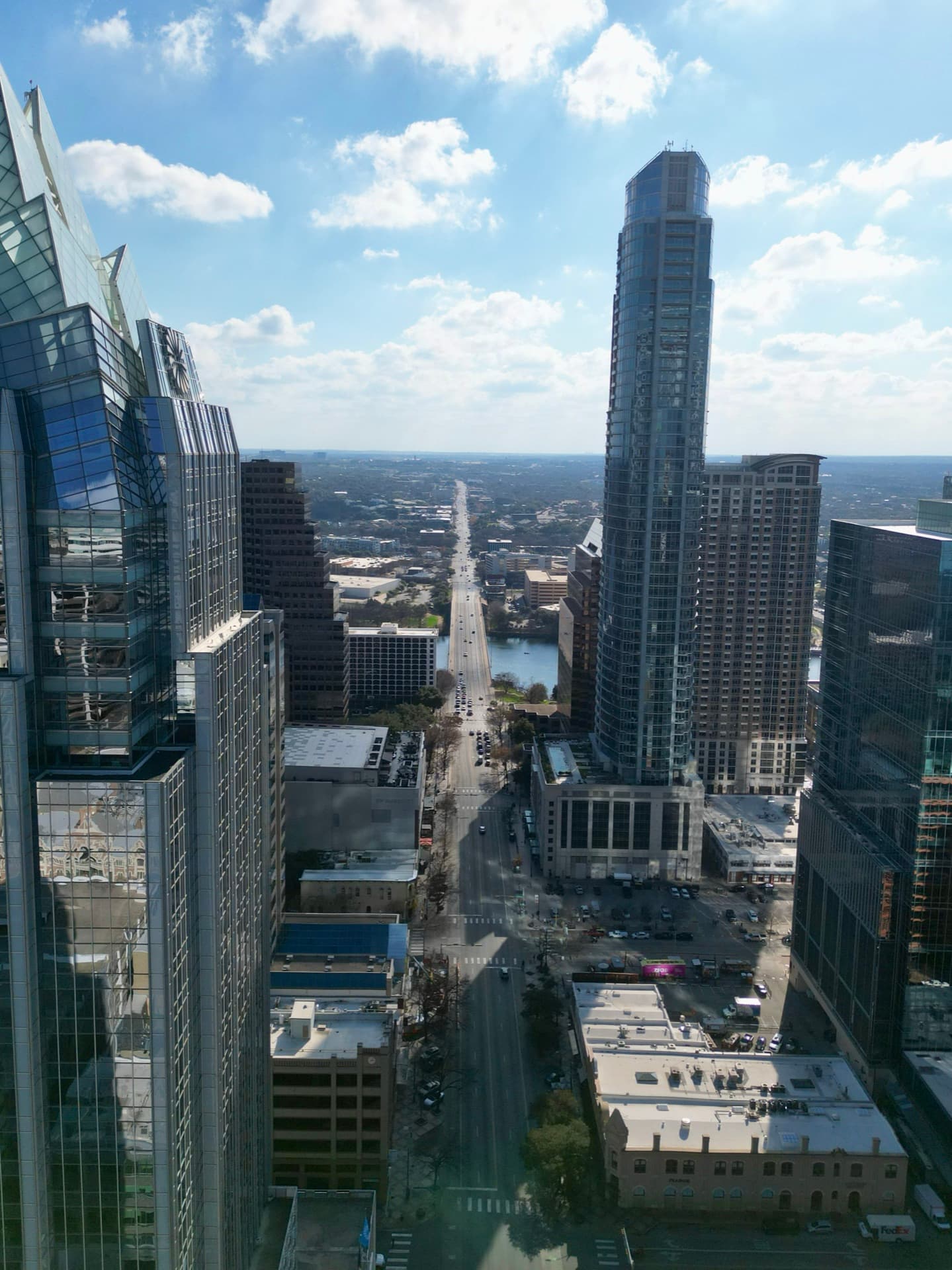 Aerial drone photo looking down Congress Avenue toward Lady Bird Lake with downtown Austin skyscrapers on either side