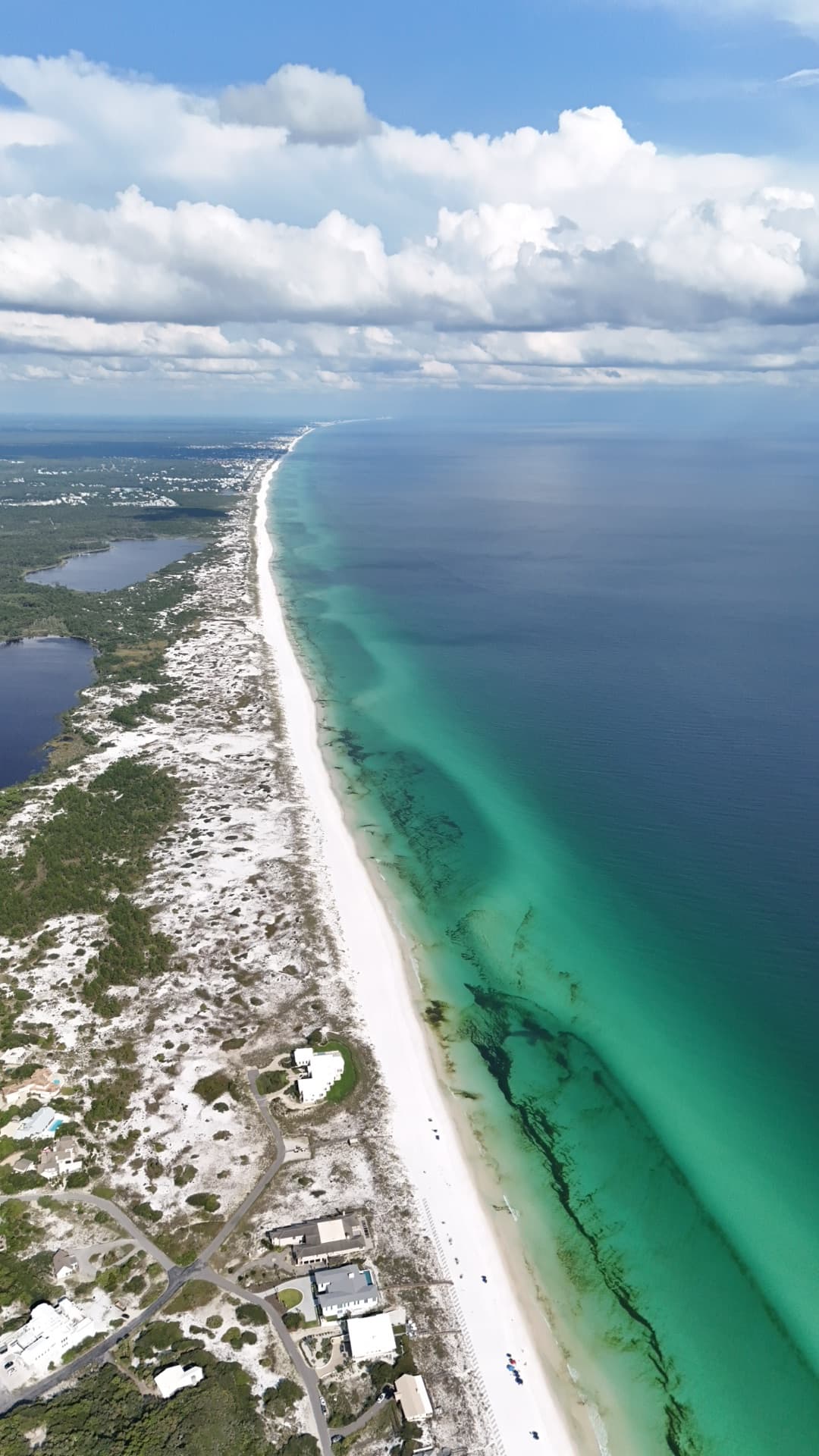 Vertical aerial of Destin 30A coastline with brilliant emerald Gulf water, white sand beach, and residential dune development