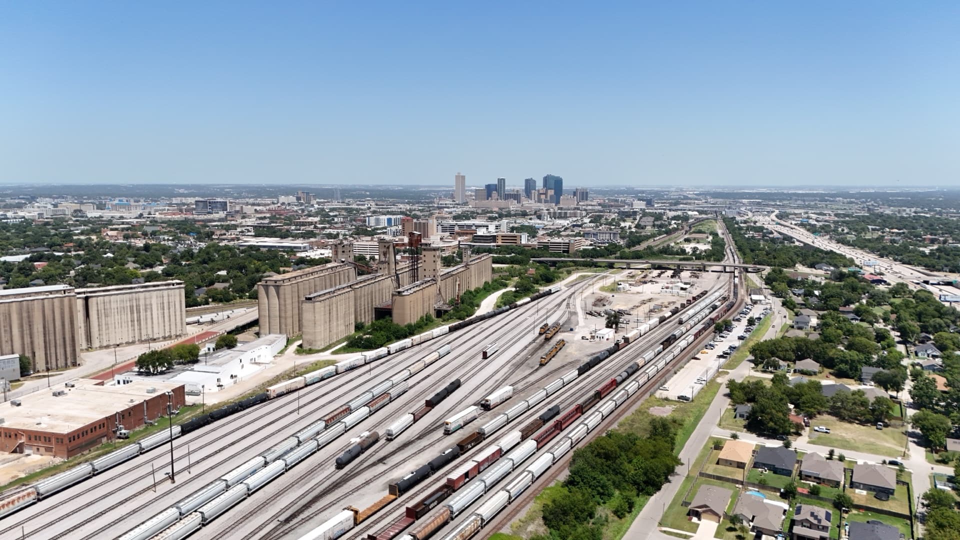 Aerial drone photo of Fort Worth skyline with large grain elevator silos and extensive rail yard in the foreground