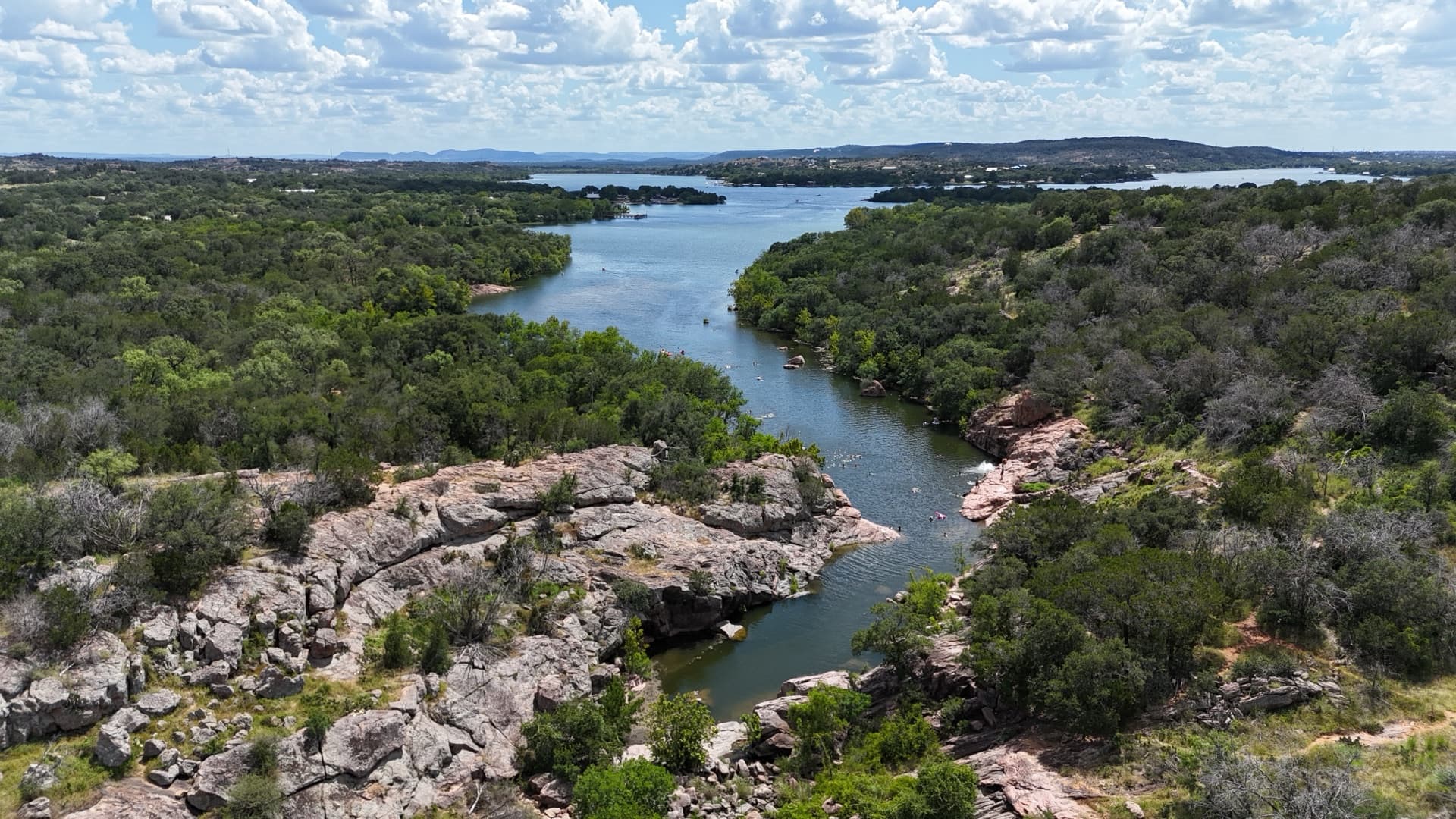 Aerial drone photo of Texas Hill Country lake canyon with pink granite bluffs, cedar trees, and blue-green water