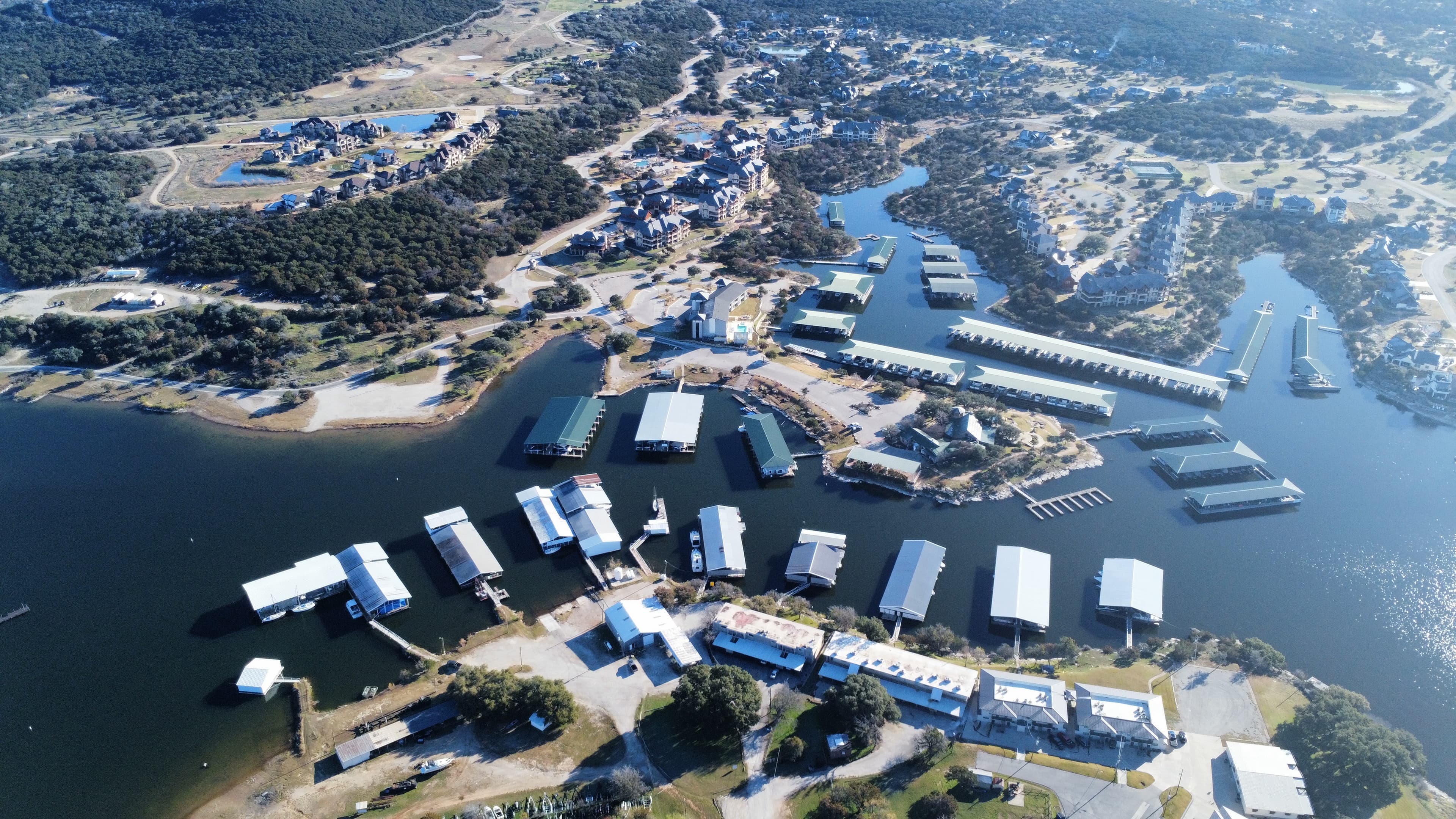 High-altitude aerial survey of Texas lake marina showing boat slips, docks, shoreline development, and Hill Country landscape