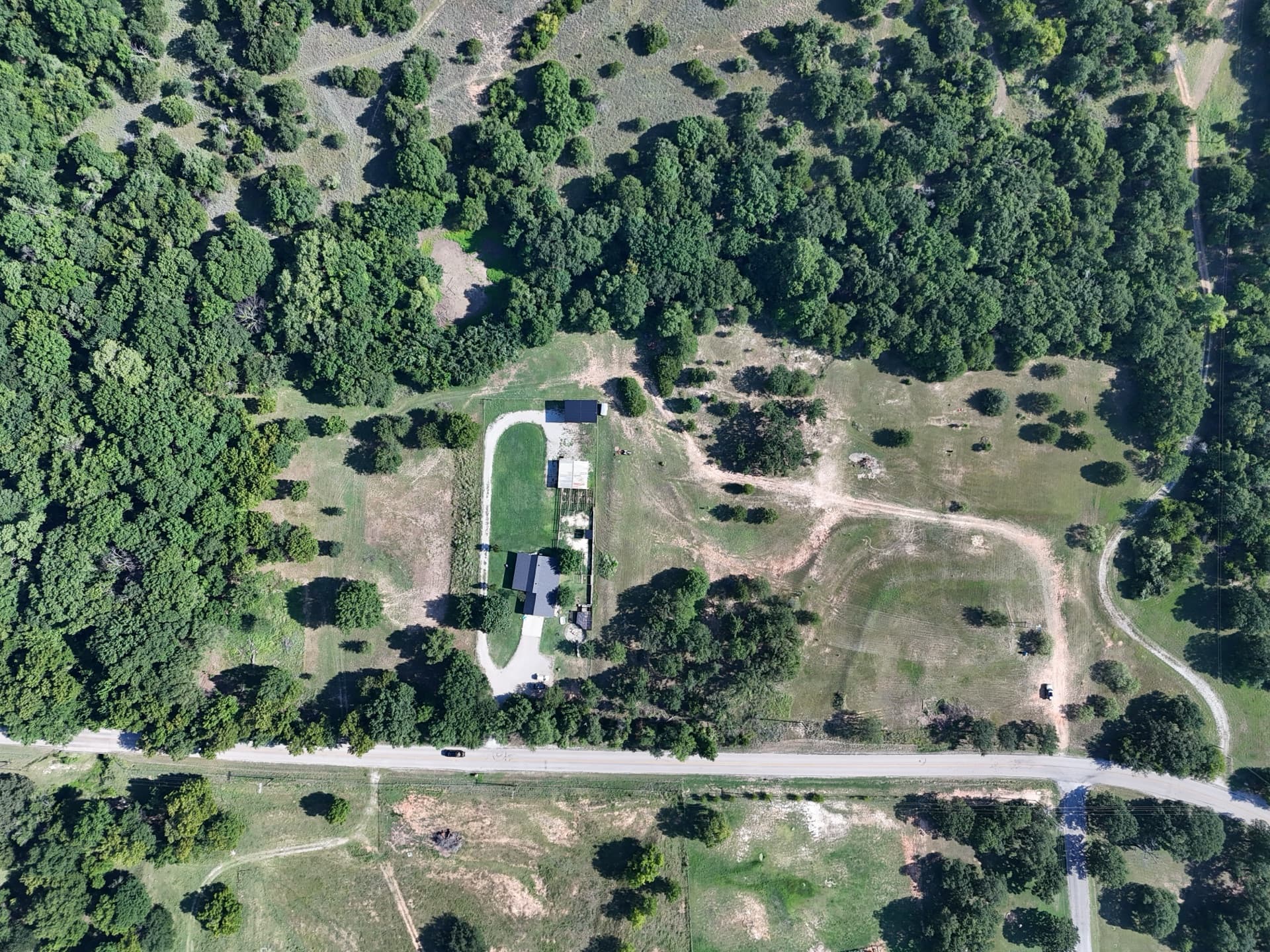 Straight-down aerial overview of a future homesite on Harwell Lake Road showing the existing house, driveway, well, and surrounding oak tree lines