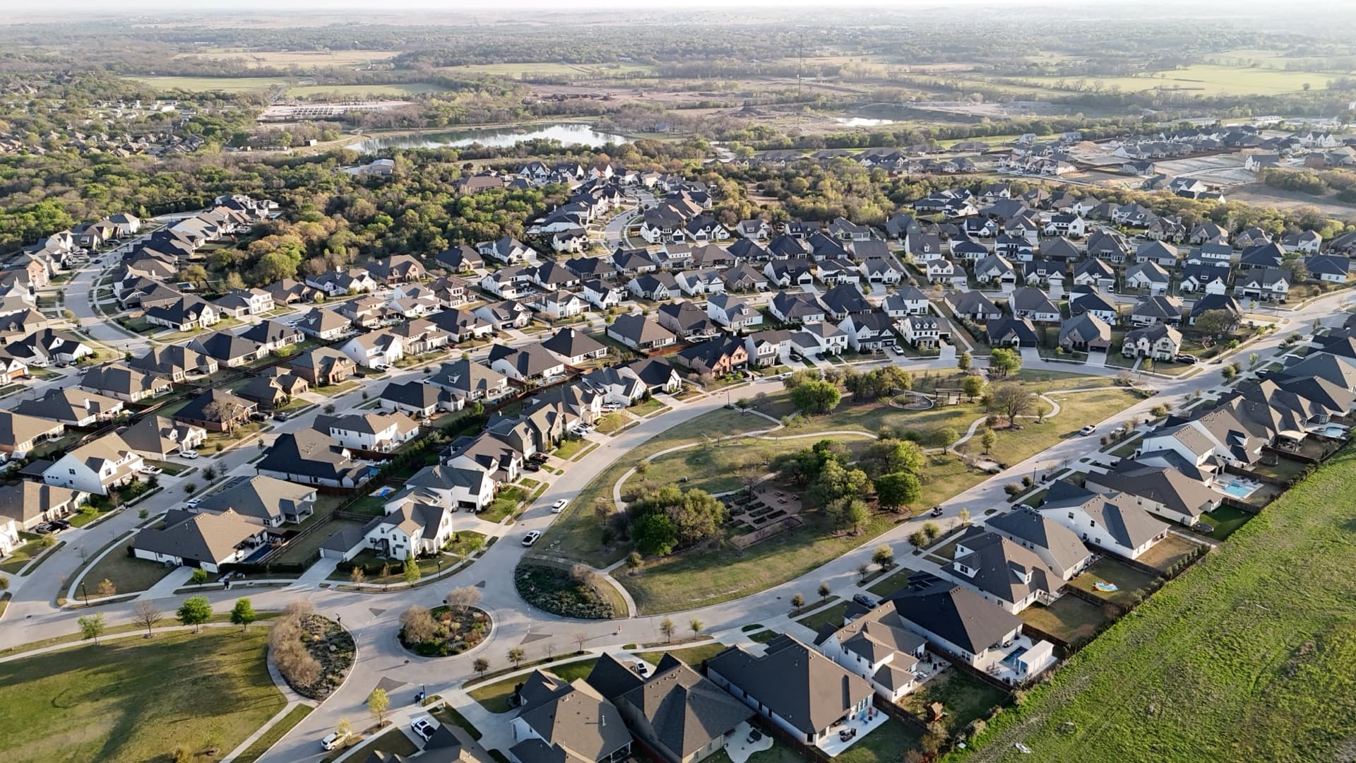 Aerial drone photo of suburban neighborhood with homes, streets, and green spaces